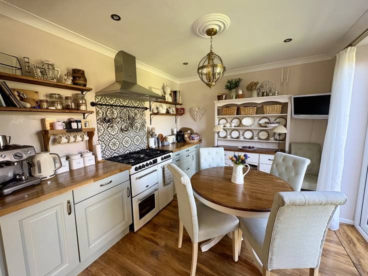 A cream painted kitchen with an oak table and dresser